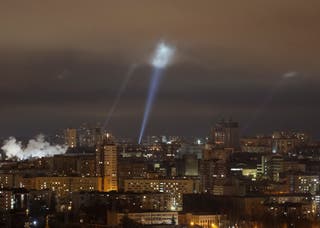 Ukrainian service personnel use searchlights as they search for drones in the sky over the city during a Russian drone strike